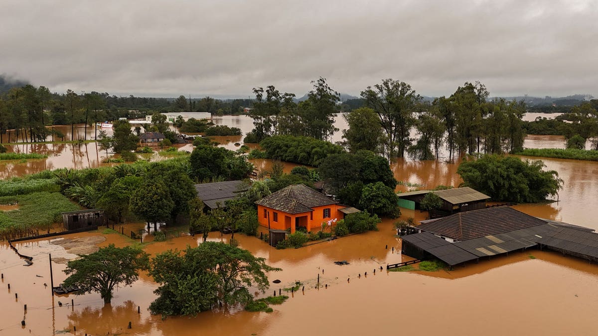 Brown waters flood an area of Capela de Santana, Rio Grande do Sul state, Brazil. An orange house sits in the middle of the flooded neighborhood.