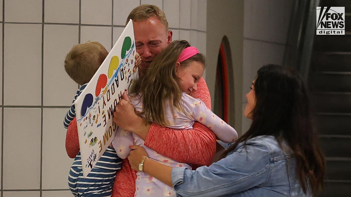 Bryan Hagerich hugs his family on the airport concourse