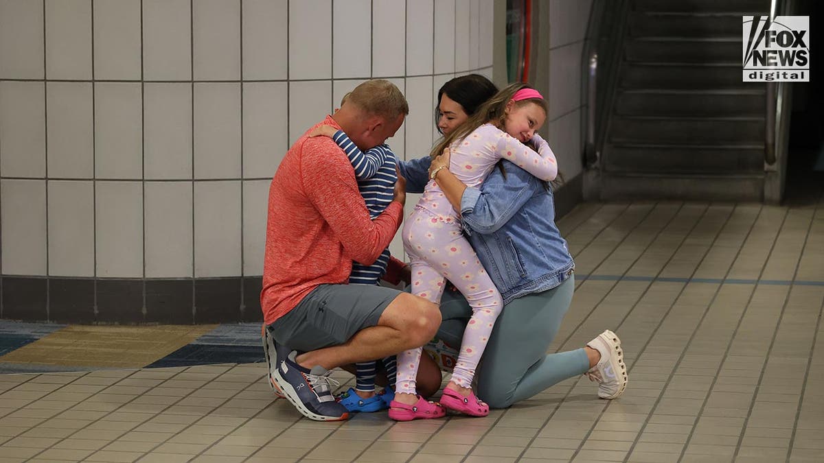 Bryan Hagerich hugs his family on the airport concourse