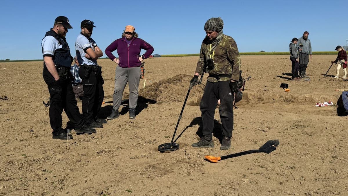 Archaeologists using metal detector on soil