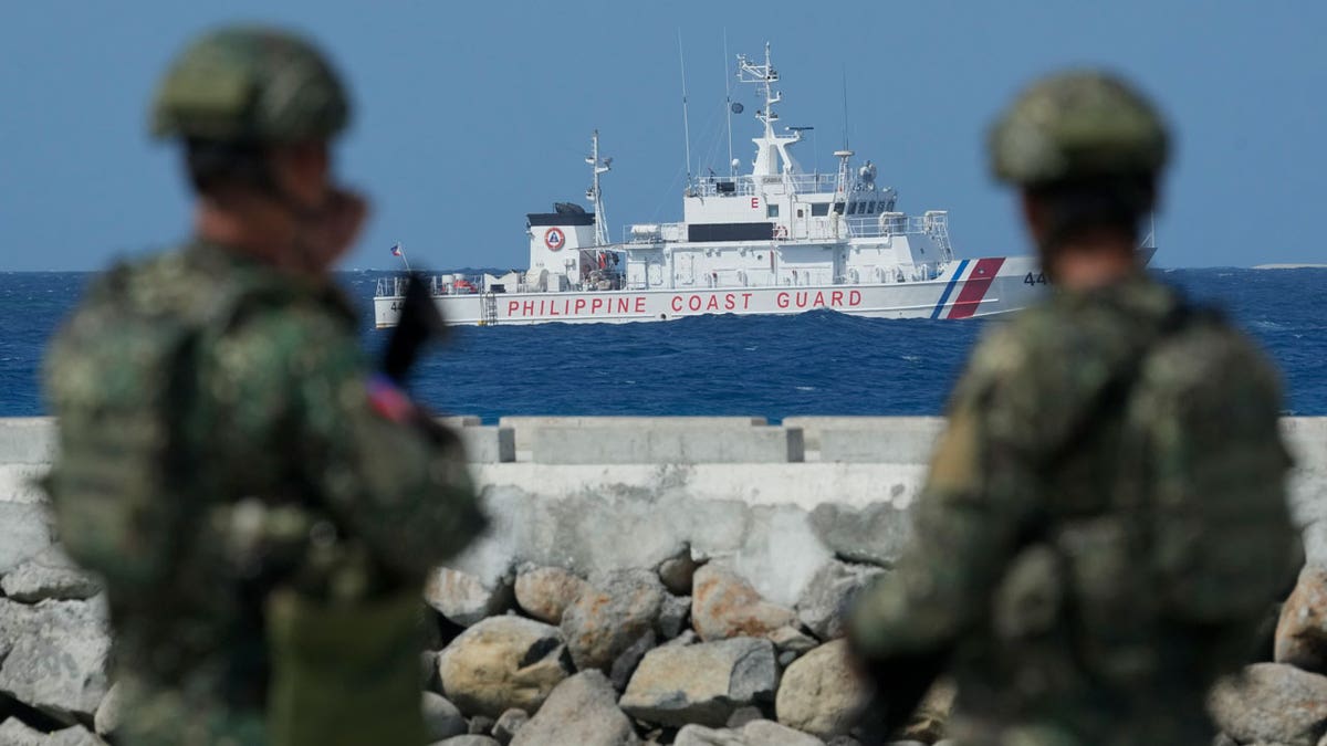 Philippine troops watch a Philippine coast guard ship as they secure an area at the Philippine-occupied Thitu island