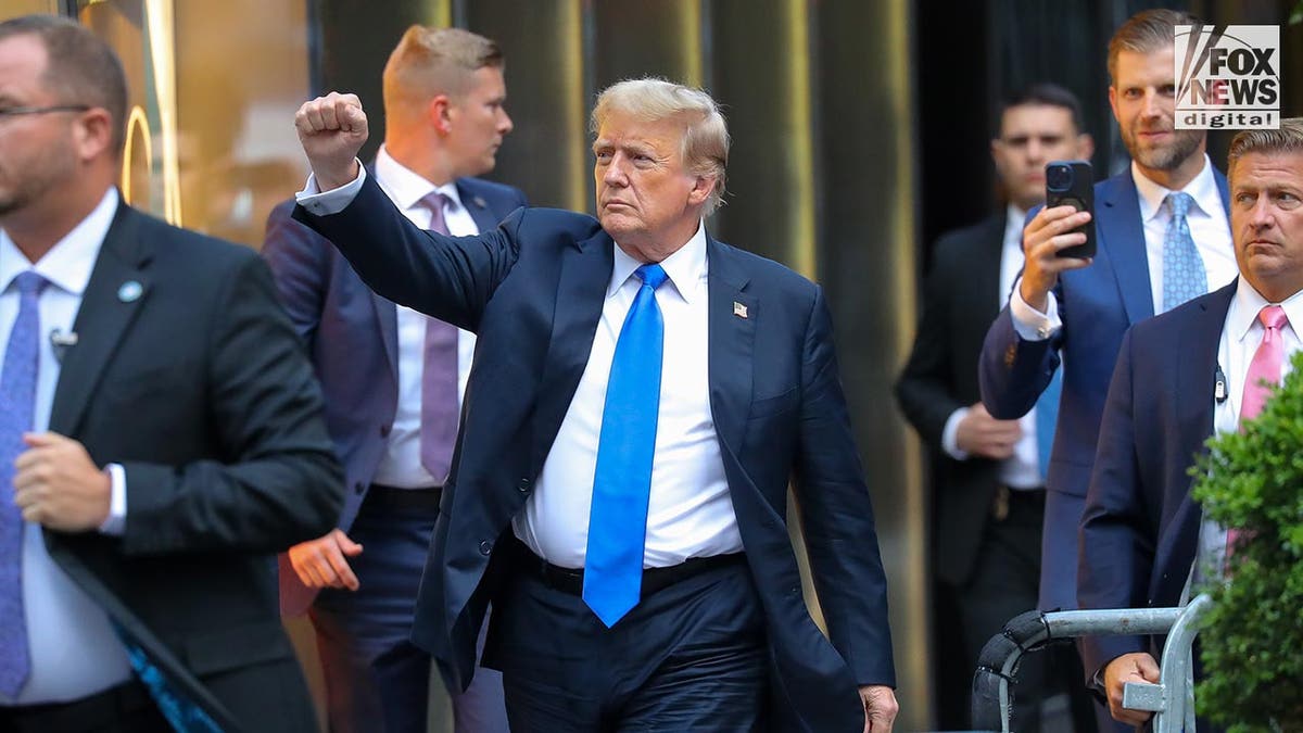 Donald Trump with right fist raised while walking on the street