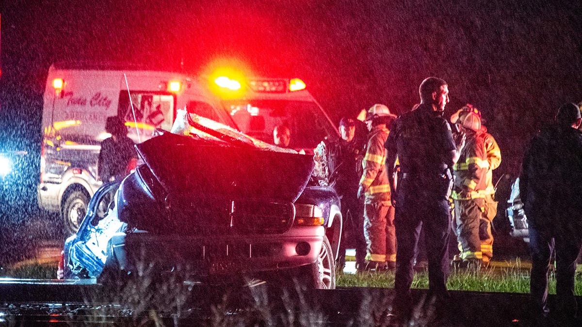 Emergency crews surround a crashed car on railway tracks