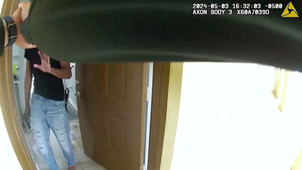 Bodycam screenshot of Roger Fortson answering the door with a gun as a deputy points his firearm at him