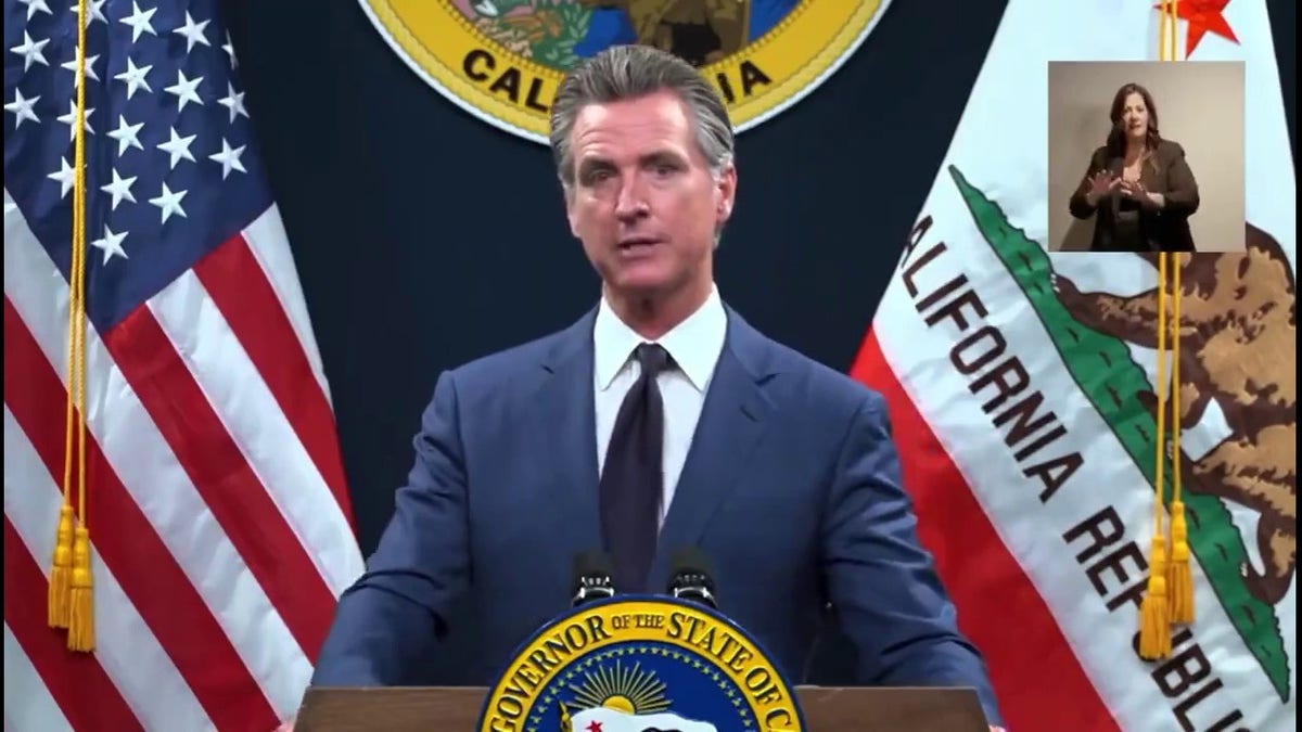 Gavin Newsom at press conference in front of US, California flags