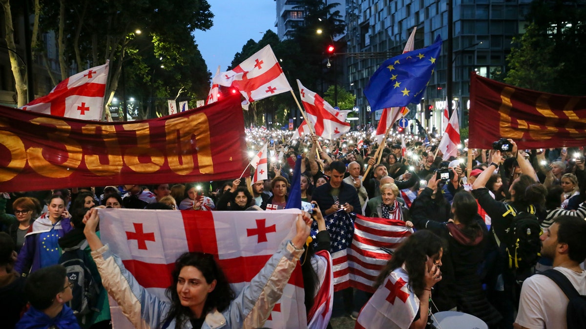 Demonstrators with Georgian national, U.S. and E.U. flags rally during an opposition protest against the foreign influence bill and celebration of Independence Day.