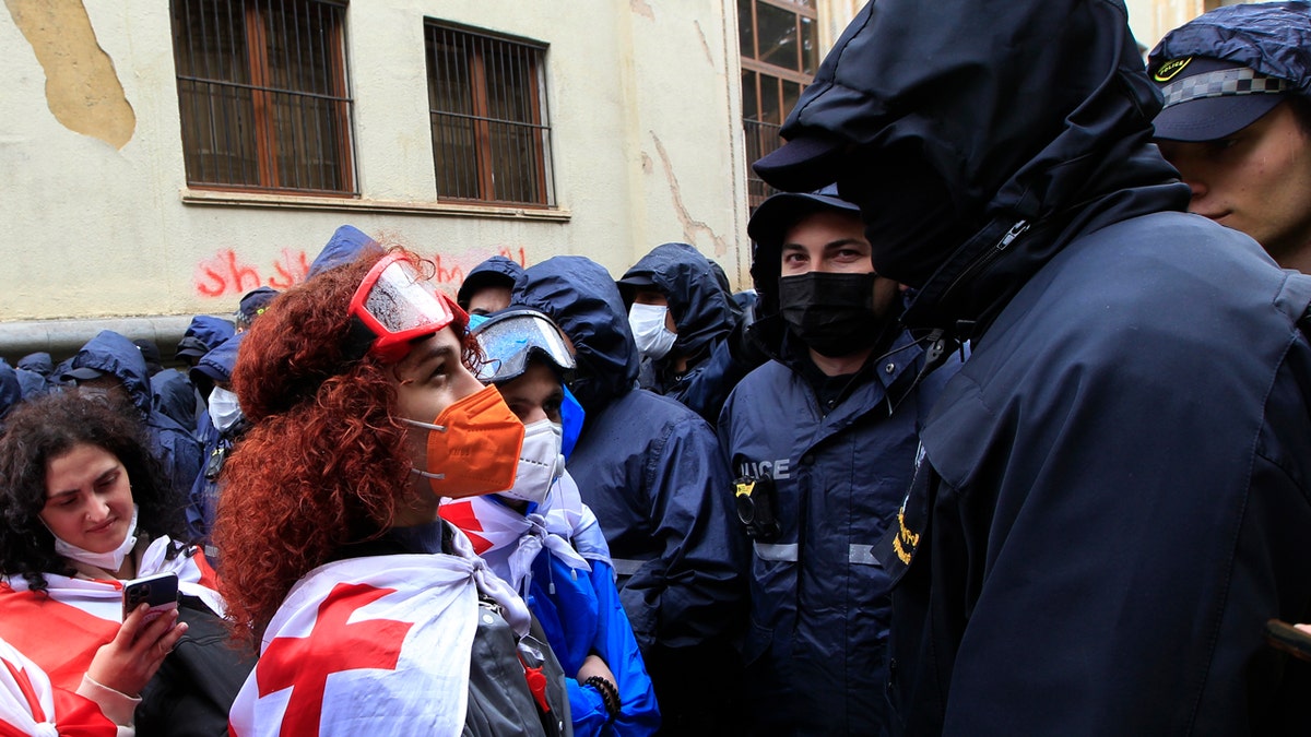 A demonstrator wears a national flag as she argues with the police that blocked the road towards the Parliament building during an opposition protest against "the Russian law" in the center of Tbilisi, Georgia