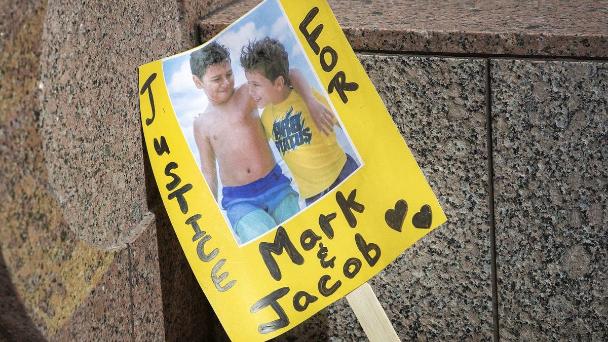 A sign shows an image of Mark Iskander, 11, left, and his brother Jacob, 8