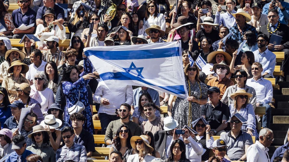 Graduados sosteniendo una bandera israelí gigante