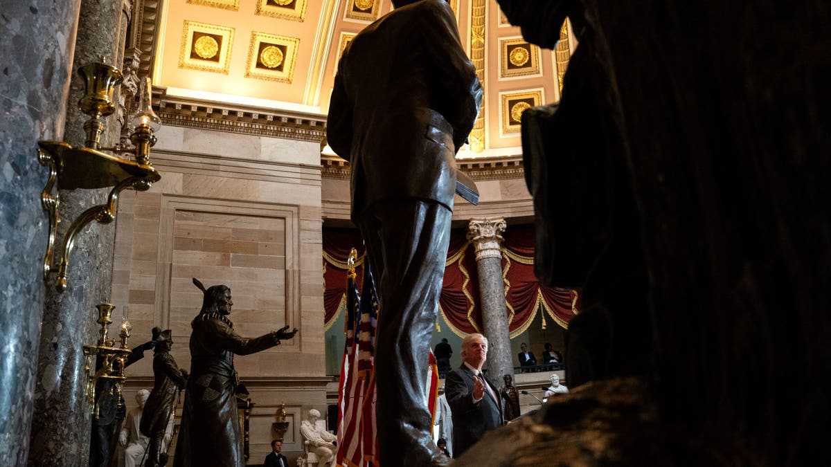 Rev. William Franklin Graham III gestures to the statue of his late father as he speaks