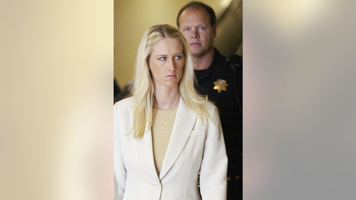 Amber Frey wearing a white blazer and tan sweater in a courtroom