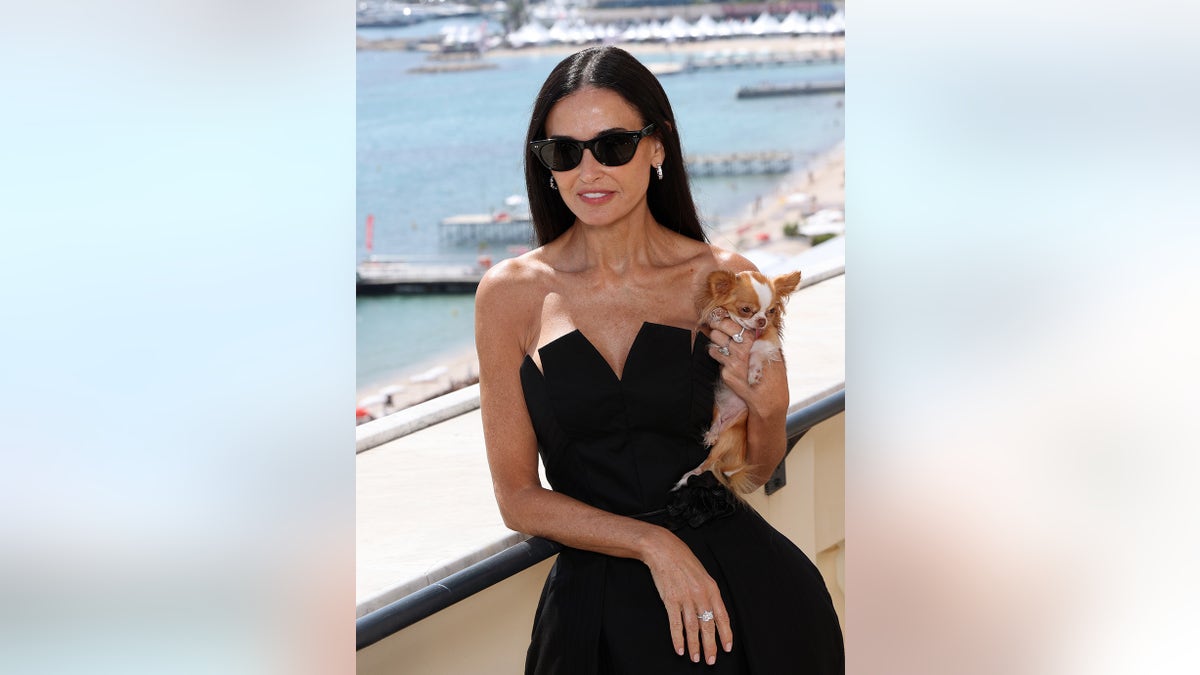 Demi Moore wearing a black strapless dress holding her dog