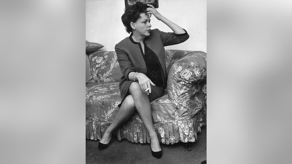 Judy Garland sitting connected a sofa and stroking her hair