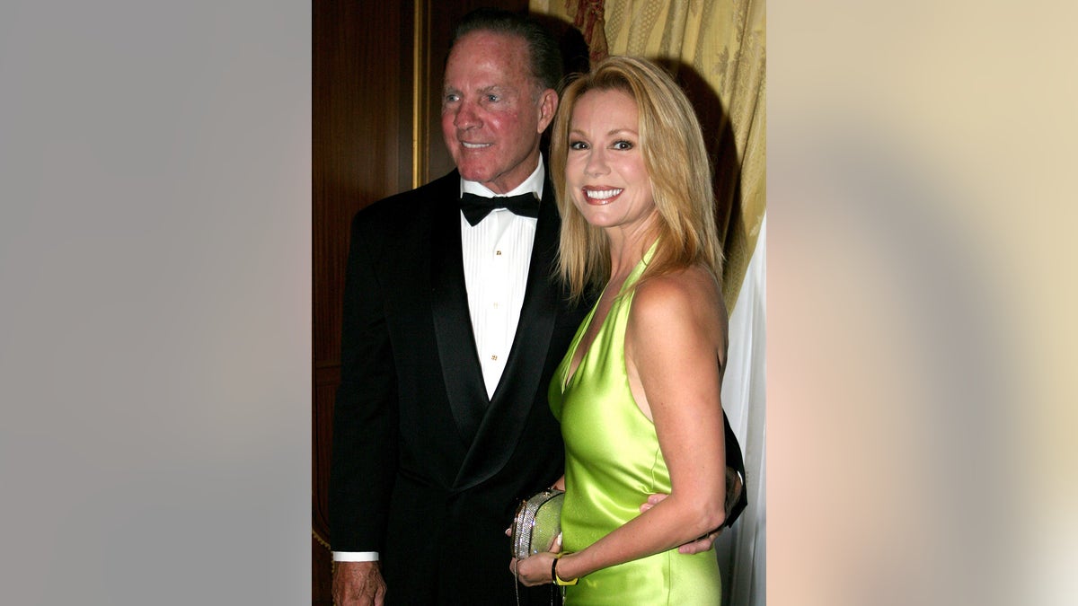 Kathie Lee Gifford wearing a satin green-yellow dress next to Frank Gifford in a suit and bow tie.