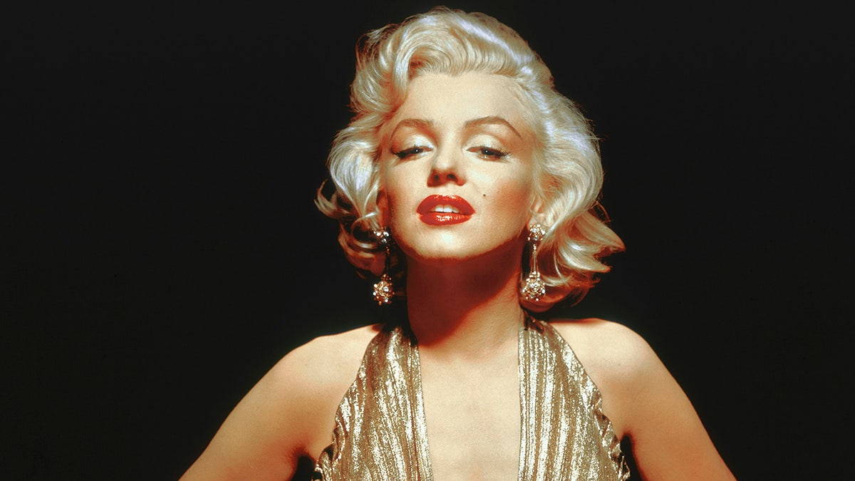 A close-up of Marilyn Monroe wearing a gold halter dress