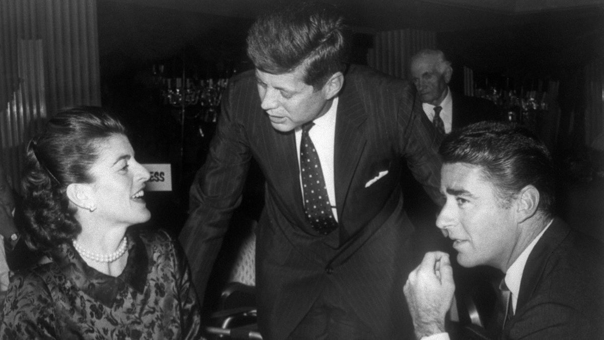John F. Kennedy talking to his sister Patricia while Peter Lawford listens