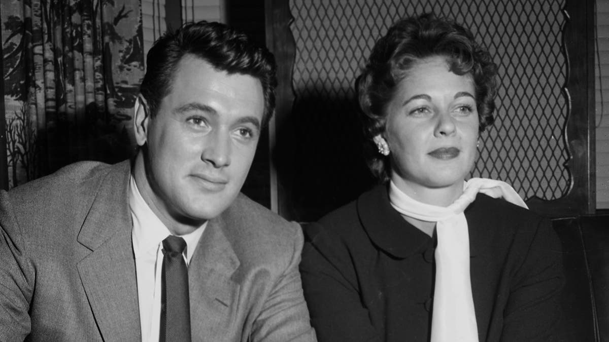 A close-up of Rock Hudson and his wife Phyllis Gates looking serious