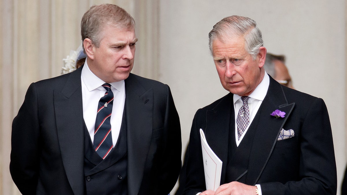 Prince Andrew looking at King Charles as they both wear dark matching suits