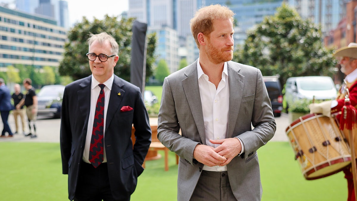Prince Harry walking outdoors in between two people