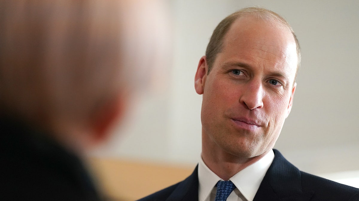 A close-up of Prince William listening to a woman speak