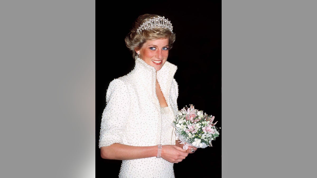 Princess Diana wearing a white dress holding a bouquet of flowers