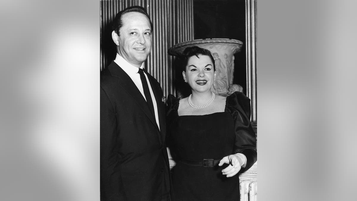 Sid Luft smiling next to Judy Garland in black dress
