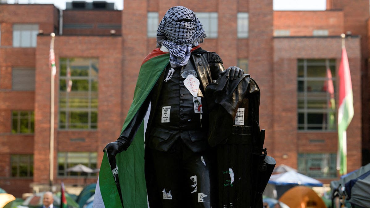 A statue of George Washington tied with a Palestinian flag and a keffiyeh inside a pro-Palestinian encampment is pictured at George Washington University
