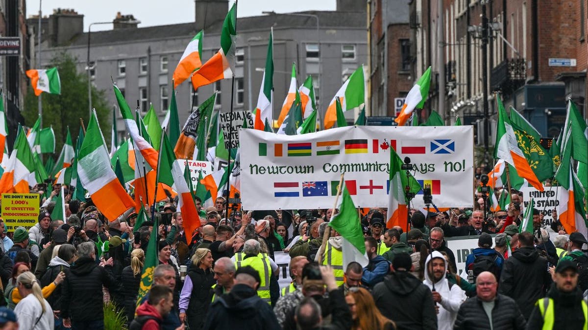 Thousands of Irish protesters carrying Irish flags protest against mass im