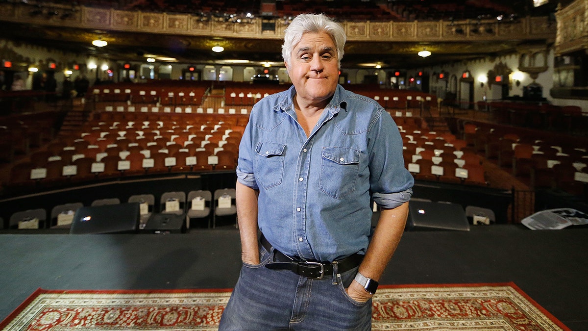 Jay Leno standing on stage in front of an empty theater