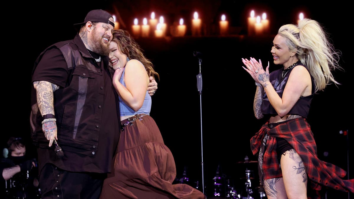 Jelly Roll hugs his daughter on stage while his wife applauds