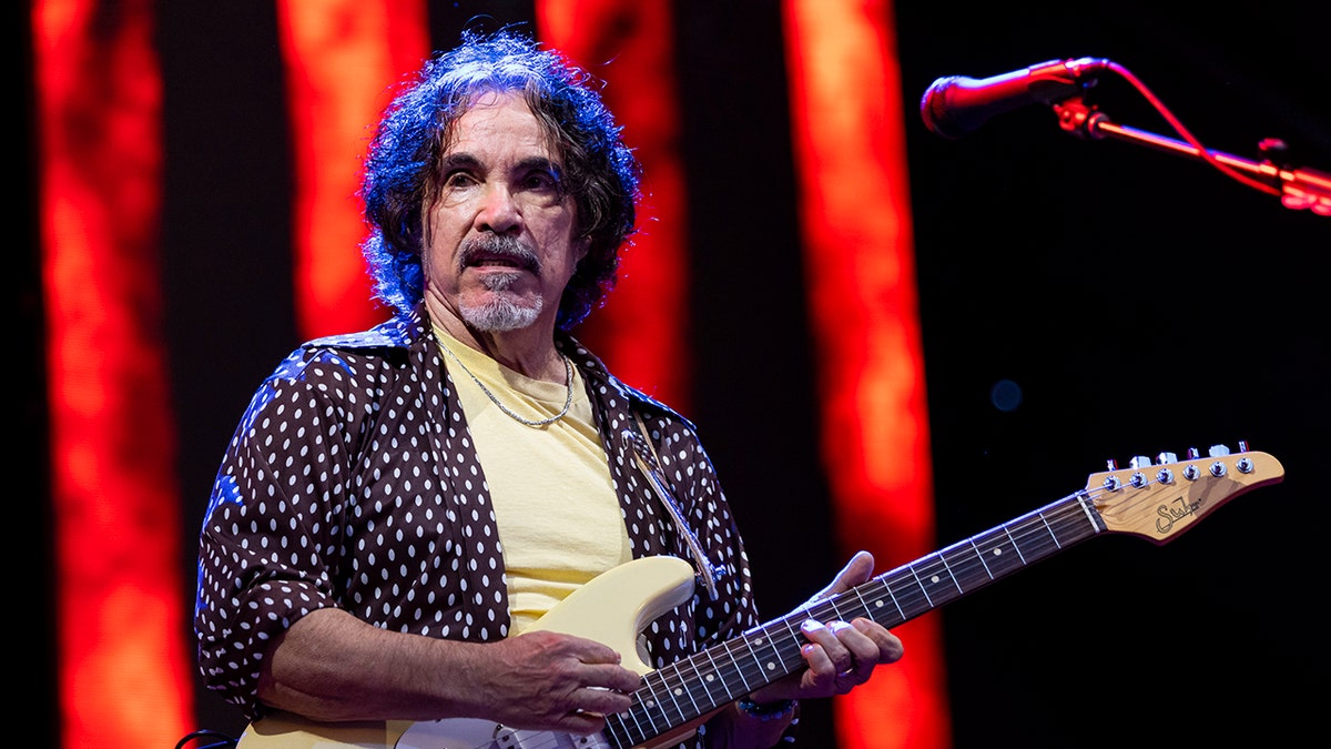 John Oates playing guitar on stage