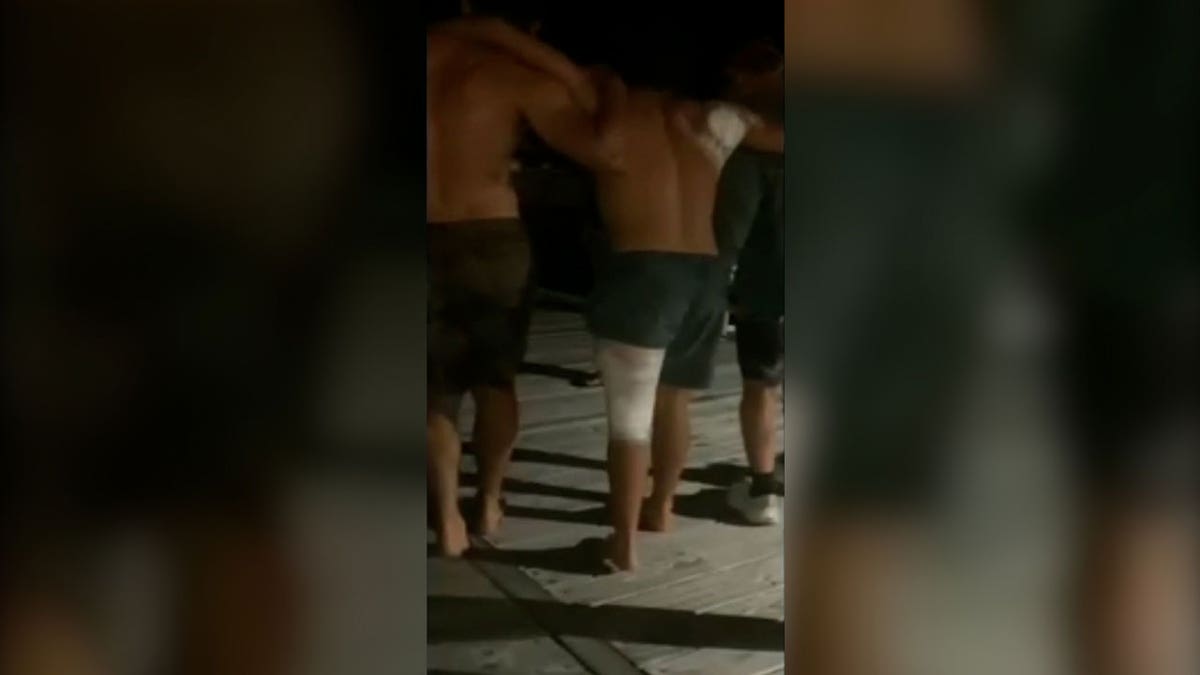 man with injured shoulder and back walk with help of friends