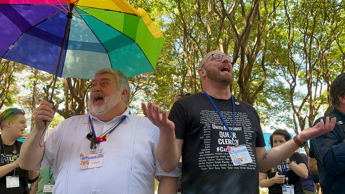 The Rev. David Meredith and the Rev. Austin Adkinson sing during a gathering of those in the LGBTQ community and their allies outside the Charlotte Convention Center