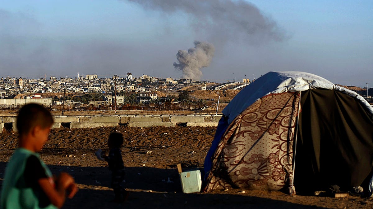 smoke rising over Gaza in background, tent in foreground