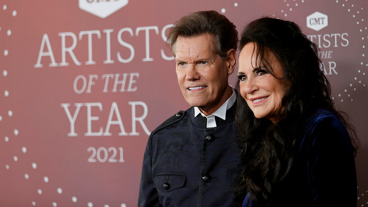 Randy Travis and Mary Travis posing at a side angle on the red carpet