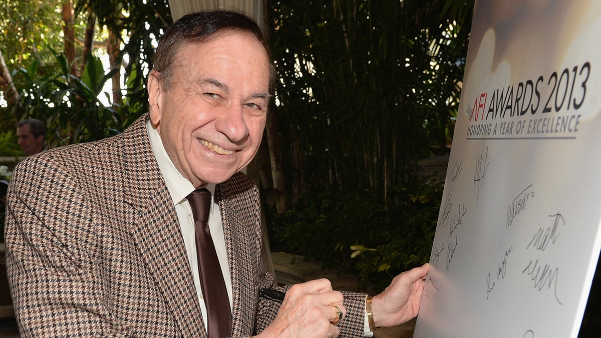 Richard M. Sherman smiling and signing a poster