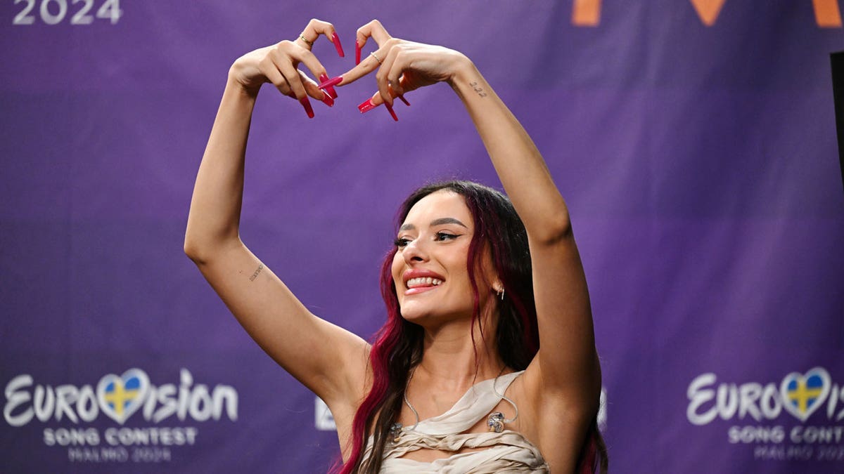 Israeli Eurovision Contestant Eden Golan Surrounded By Security, Boos And Applause Ahead Of Finals Eden Golan, representing Israel, makes a heart with her fingers during a press meeting with the entries that advanced to the final after the second semi-final of Eurovision 2024.