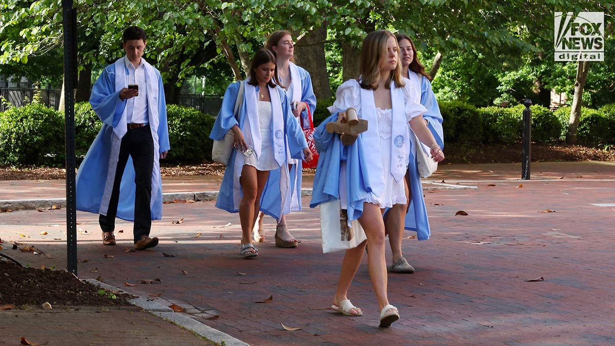 Graduates walk along campus in their graduation outfits