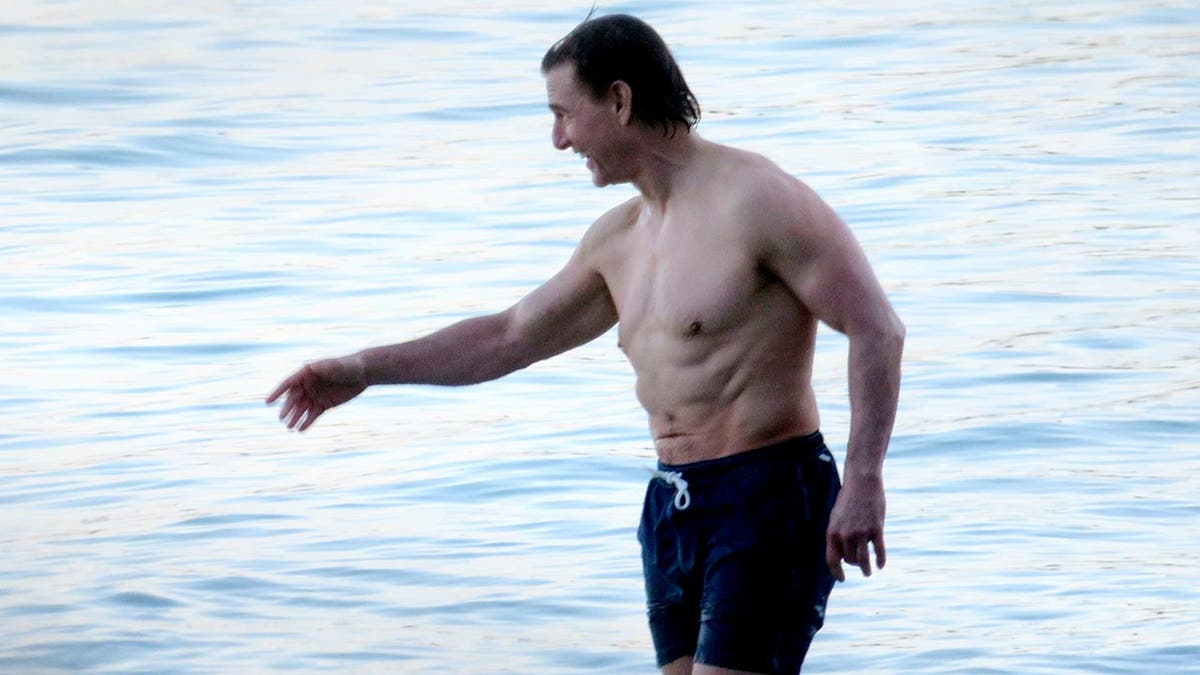 Tom Cruise shirtless in the sea wearing blue swim trunks