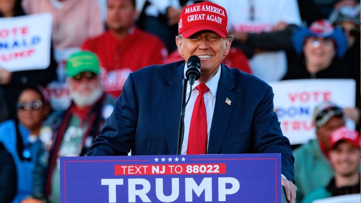 Former President Trump wearing a red MAGA hat speaks at a rally