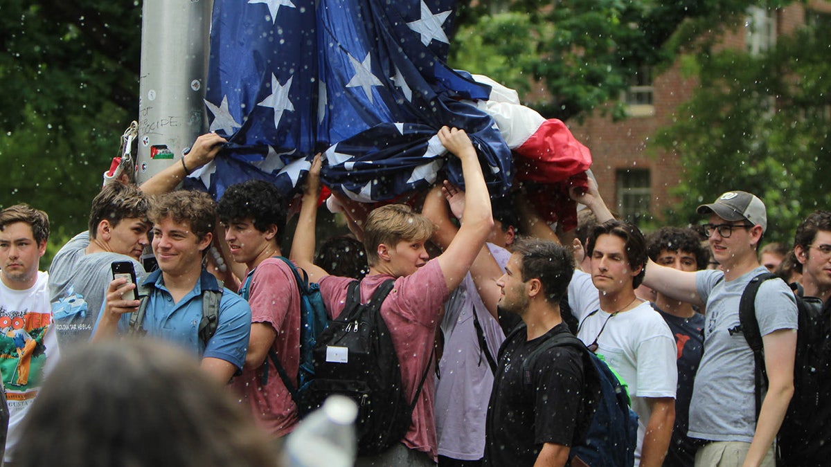 یو این سی چیپل ہل کے طلباء کیمپس میں احتجاج کے دوران امریکی پرچم اٹھائے ہوئے ہیں۔
