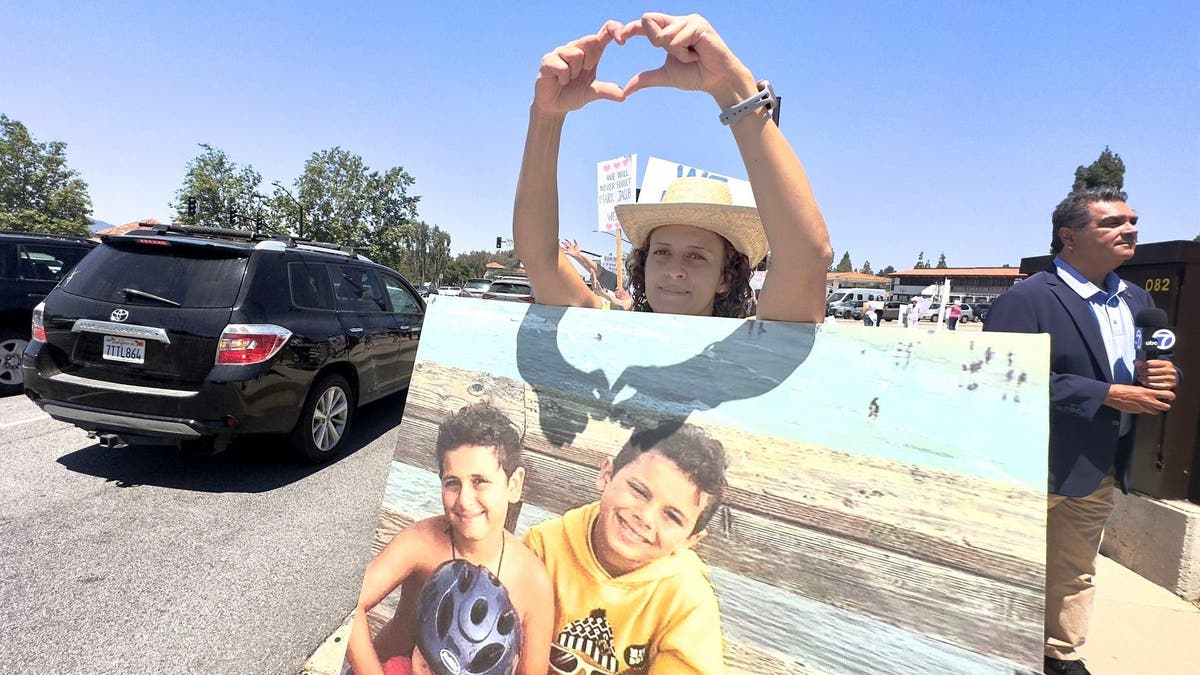 Miriam Guirguis, aunt of Mark and Jacob Iskander, stands with a photo of the two boys at a protest against speeding