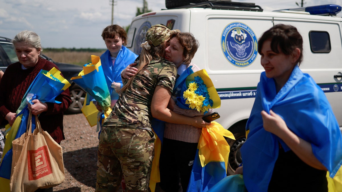 A Ukrainian military officer embraces civilians and prisoners of war after a prisoner swap
