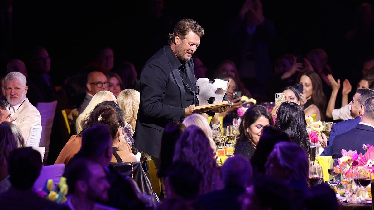 Blake Shelton in a black suit amongst a crowd of female attendees