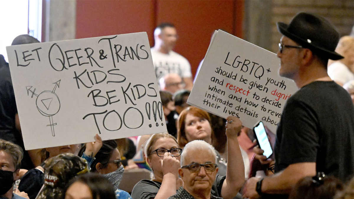 People hold up signs in support of gay and transgender students.