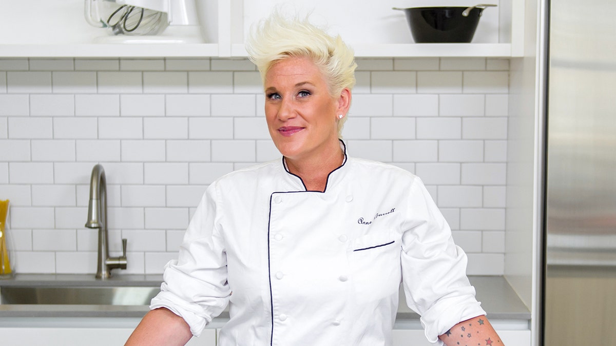 Chef Anne Burrell standing at a kitchen table 