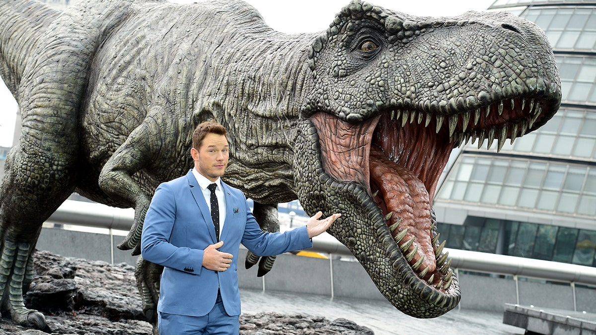 Chris Pratt standing next to a dinosaur at the premiere of Jurassic World.