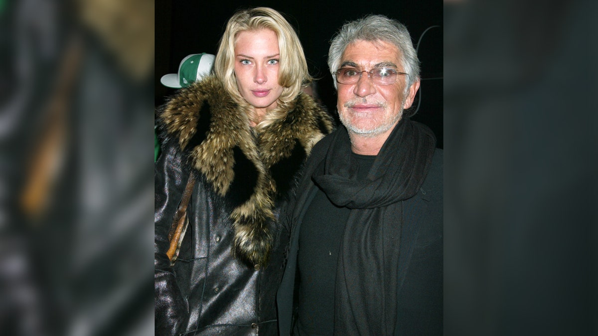 Model Crystal McKinney sports black leather jacket with fur trim next to fashion designer Roberto Cavalli.