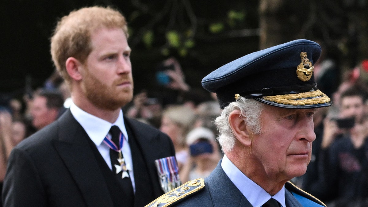 Prince Harry walking behind his father King Charles