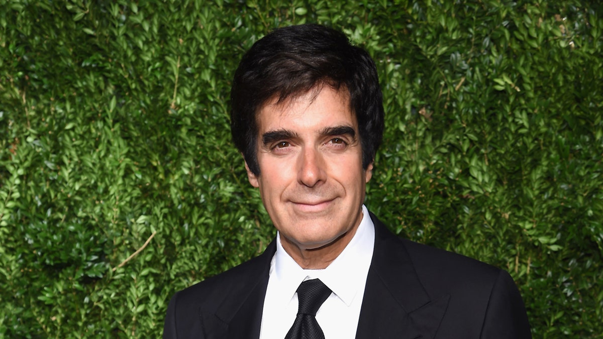 Magician david Copperfield wears black suit and tie.